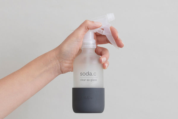 soda.c clear as glass shiny surface cleaner reusable glass bottle held in hand.