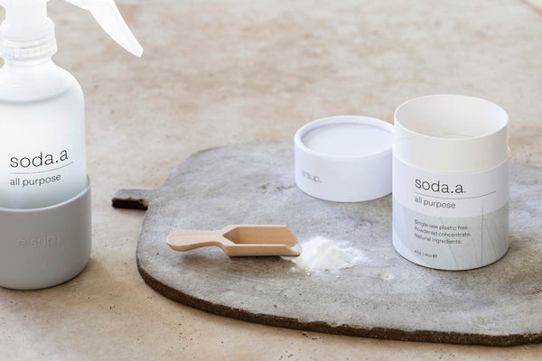 soda.a all-purpose cleaner with beautiful reusable glass bottle and scoop of powder ready for dilution.